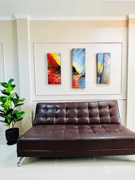 联排别墅 出租 - 棕色皮沙发特写，墙面三幅彩色装饰画与线条墙板。