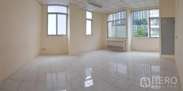 办公空间 出租在Phra Khanong, Bangkok - 50平方米办公室全景，双面大窗、网格吊顶与日光灯，空间方正。