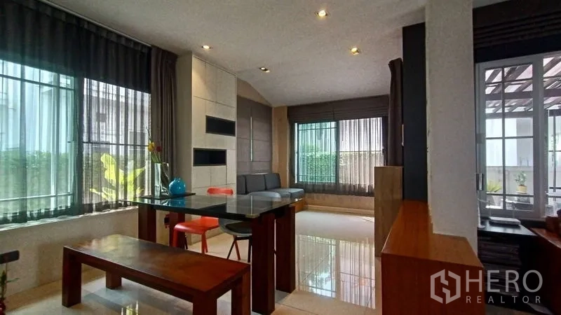 独立式住宅 出售在Prawet, Bangkok - 餐区，玻璃餐桌、长椅和面向花园的窗户，邻近露台。