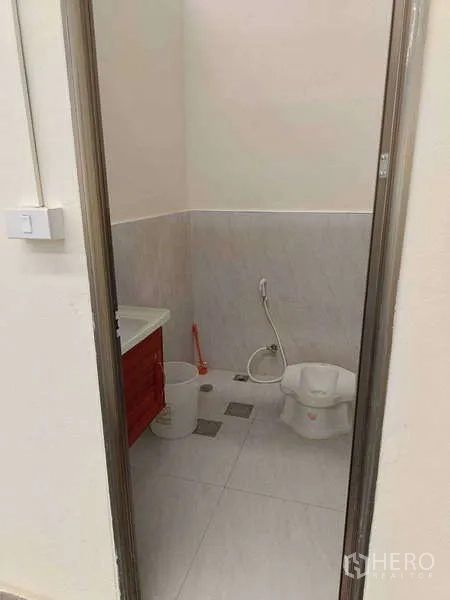 货栈 出租在Ban Phaeo, Samut Sakhon - 仓库内整洁的瓷砖卫生间，蹲式马桶、手持喷枪与洗手台。