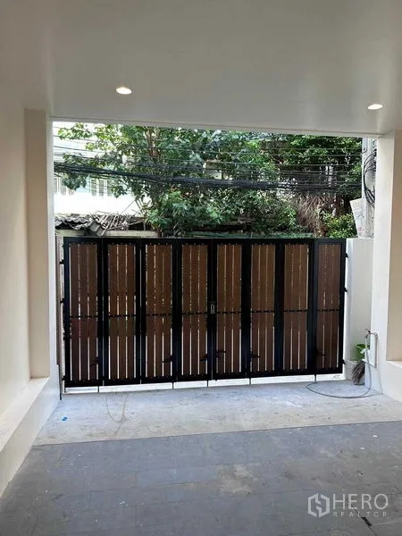 Detached House for rent in Bang Rak, Bangkok - Covered carport with a sliding metal-and-wood entry gate.