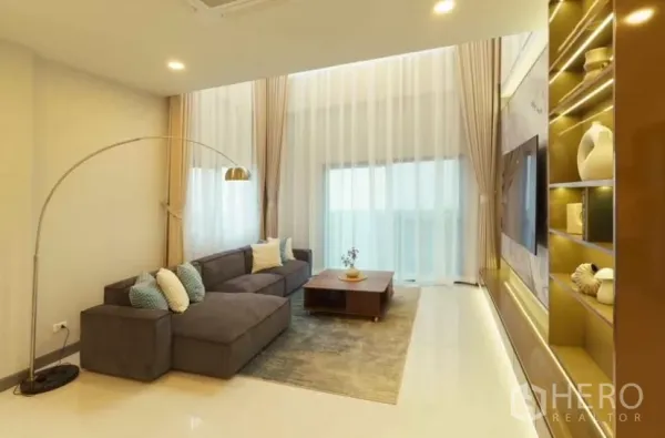 Detached House for rent or sale in Bang Phli, Samut Prakan - Bright lounge with L-shaped sofa, sheer double-height curtains and statement TV wall.