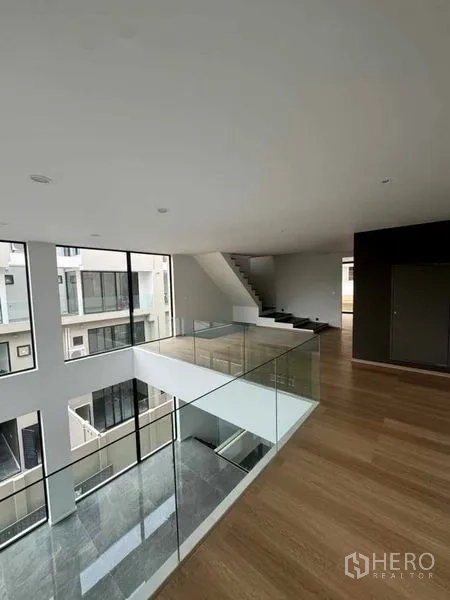 สำนักงานที่บ้าน ให้เช่าหรือขายในLat Phrao, Bangkok - ชั้นลอยมีราวกันตกกระจก มองลงสู่โถงเพดานสูงและบันได.