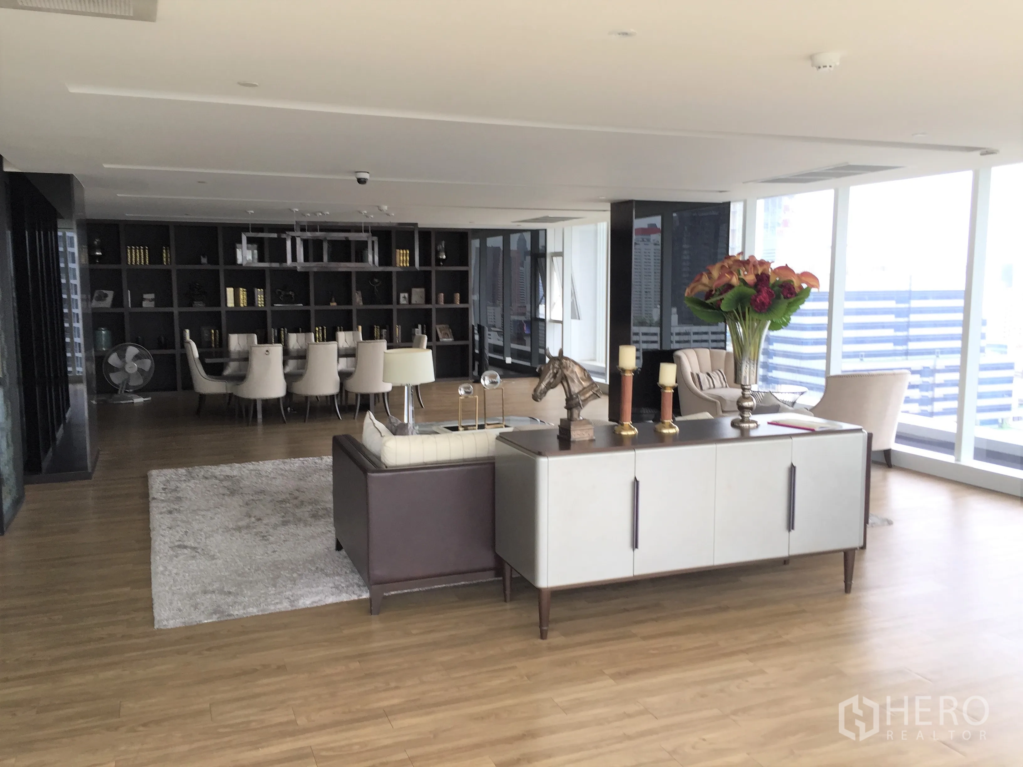 公寓 出租在Bang Rak, Bangkok - 典雅住客休息室，带书柜、沙发与城市景观。