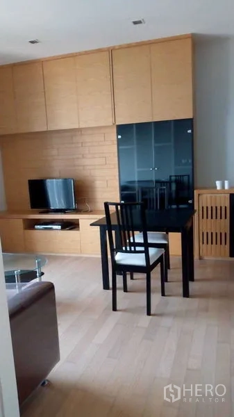 คอนโด ให้เช่าในWatthana, Bangkok - โซนห้องนั่งเล่นพร้อมผนังตู้ไม้ ทีวี และโต๊ะอาหารในคอนโดเขตวัฒนา