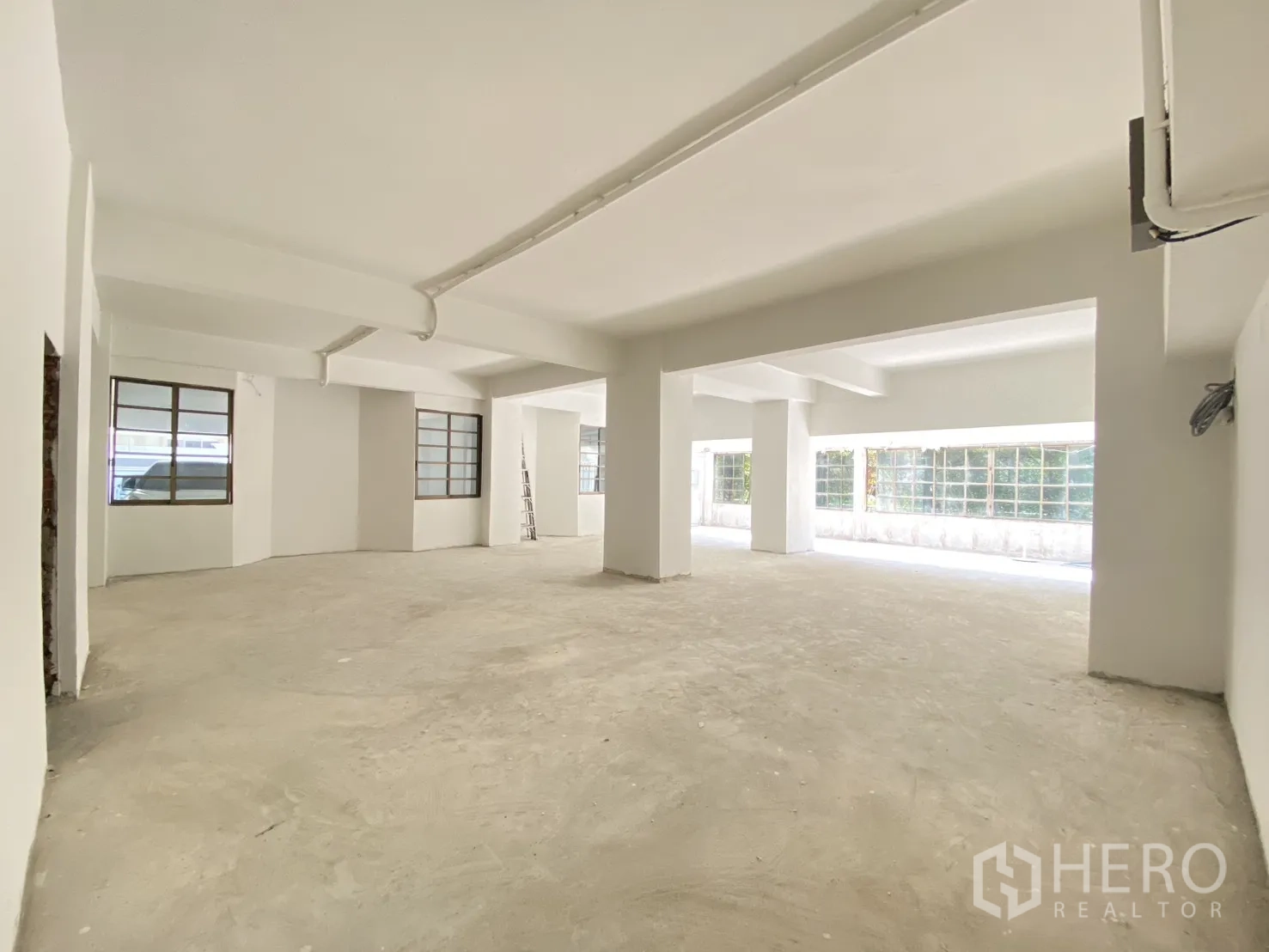 零售空间 for rent in Watthana, Bangkok - 明亮店面，设多扇窗、天花梁与外露管线。