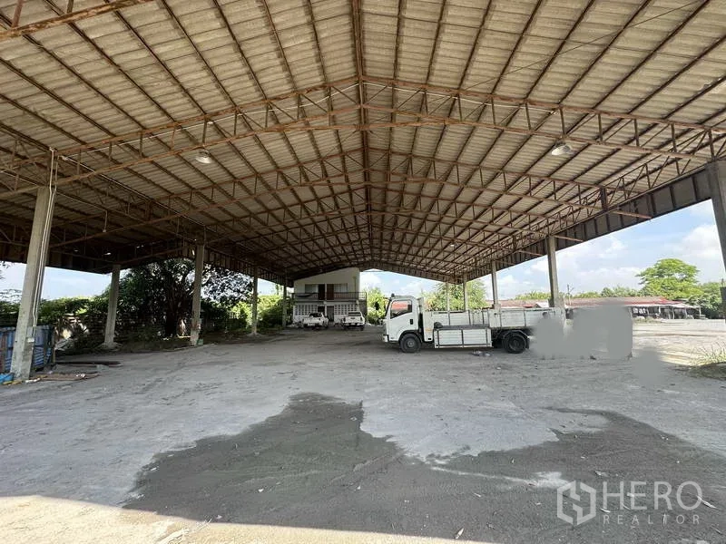 工厂 出租在Phra Nakhon Si Ayutthaya - 大型高顶装卸区，卡车停放，后方可见办公楼。
