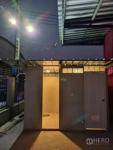 Warehouse for rent in Khlong Luang, Pathum Thani - External restroom block under a metal roof with night lighting.