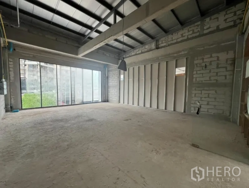 พื้นที่ขายปลีก ให้เช่า - พื้นที่เพดานสูง โครงเหล็ก โคมไฟห้อย และผนังกระจกบานเลื่อนรับแสง