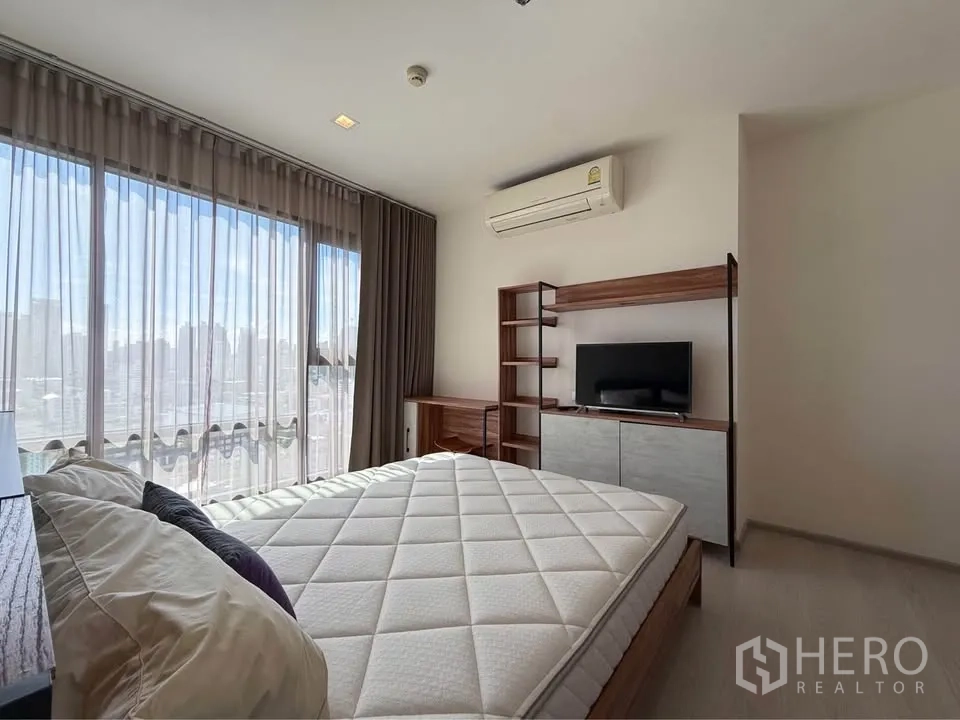 Condominium for rent in Khlong Toei, Bangkok - Bright sleeping area with large window, TV cabinet, air conditioner and city view.
