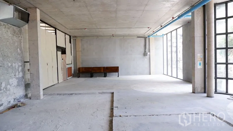 零售空间 出租在Watthana, Bangkok - 纵深长方形铺面，高挑层、风管与落地玻璃引入自然光。