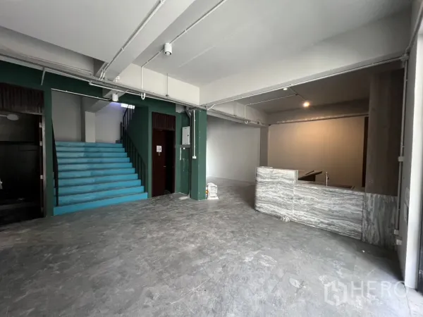 สำนักงานที่บ้าน ให้เช่าในPathum Wan, Bangkok - พื้นที่ชั้นล่างโล่ง มีบันไดสีฟ้า เพดานเปลือย และเคาน์เตอร์หิน