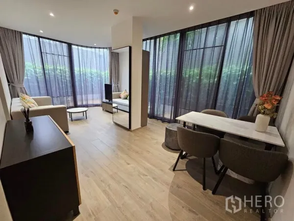 คอนโด ให้เช่าหรือขาย - ห้องนั่งเล่น-ทานอาหารแบบเปิดโล่ง มองเห็นระเบียงสวนผ่านกระจกสูง