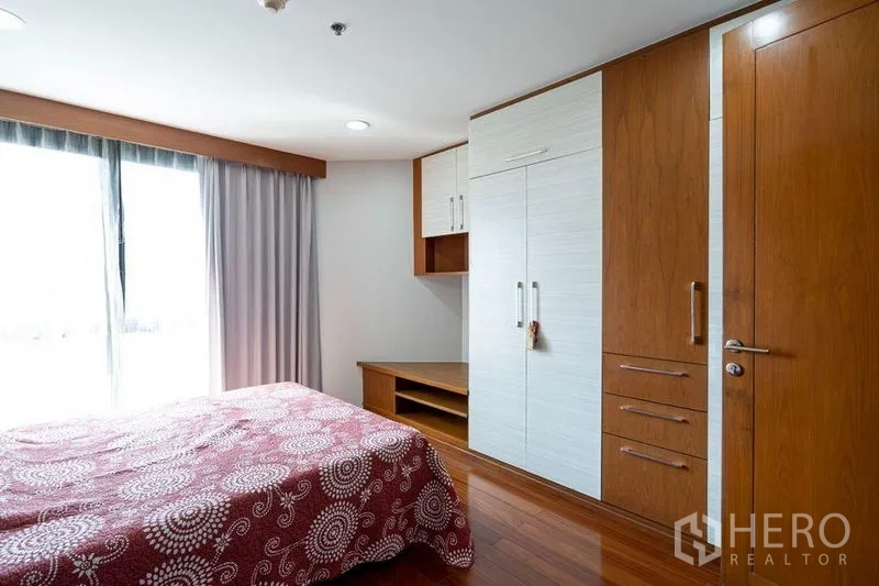 公寓 出售在Watthana, Bangkok - 温馨卧室，嵌入式衣柜、床头柜与通往阳台的门。