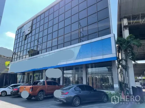 货栈 出租在Prawet, Bangkok - 玻璃幕墙商业建筑外立面，前方设停车位。