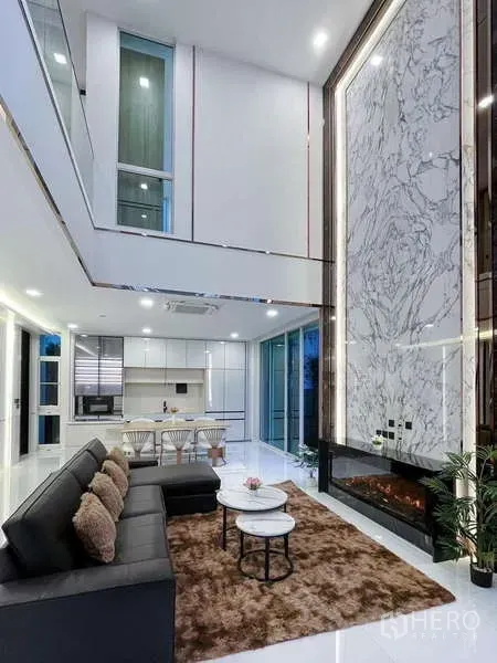 Detached House for rent in Bueng Kum, Bangkok - Double-height living room with marble feature wall, sleek fireplace and open-plan kitchen-dining.