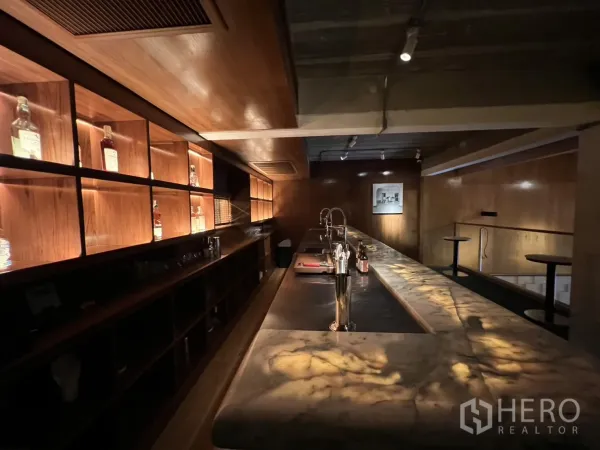 零售空间 出租在Watthana, Bangkok - 吧台近景，木质灯箱酒架与清洗水槽。