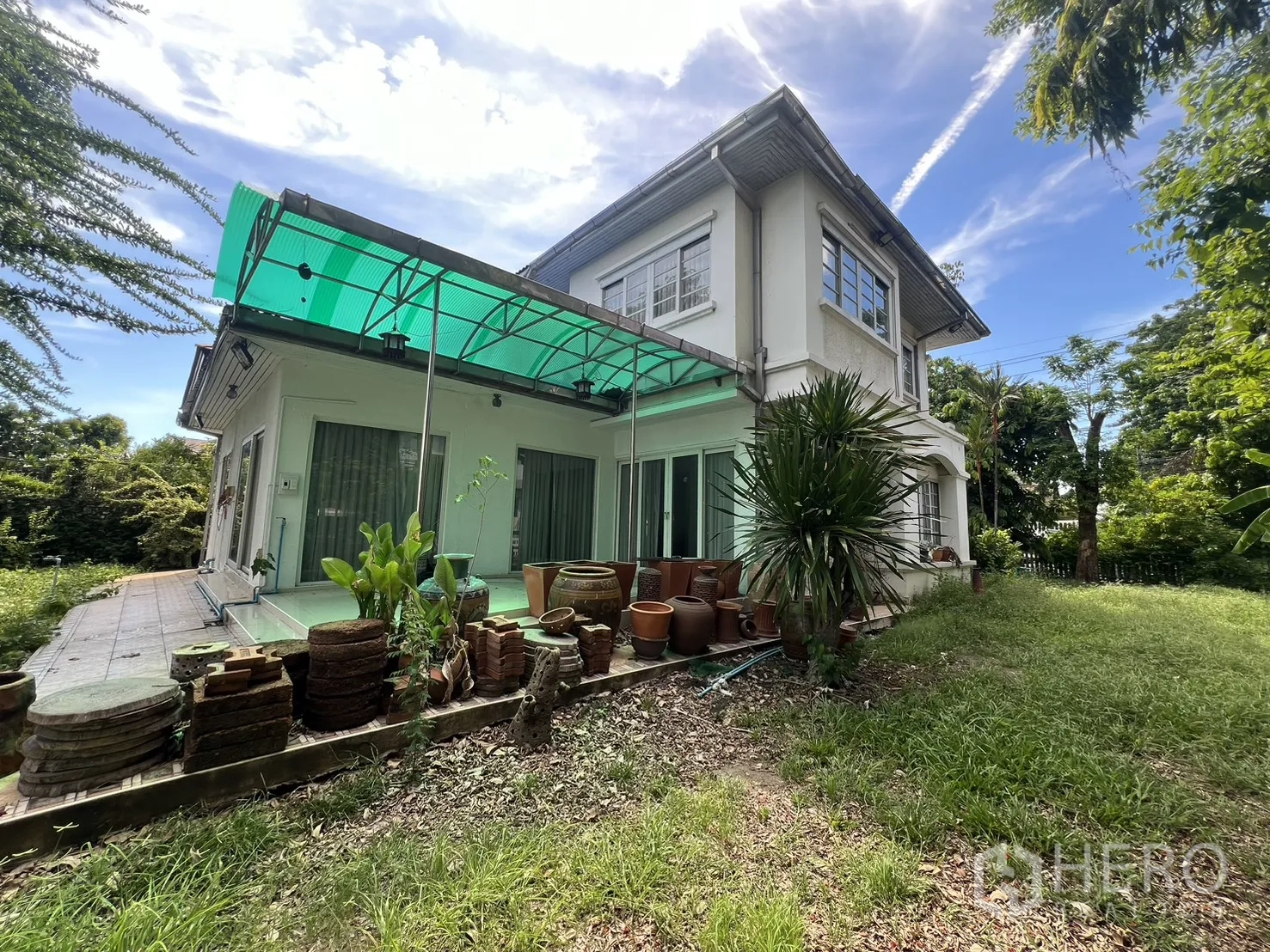 Detached House for sale in Saphan Sung, Bangkok - Rear exterior of two-storey white house with canopy and grassy yard.