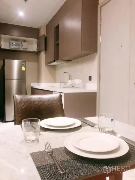 Condominium for rent in Watthana, Bangkok - Compact dining and kitchenette with marble-top table and built-in cupboards.