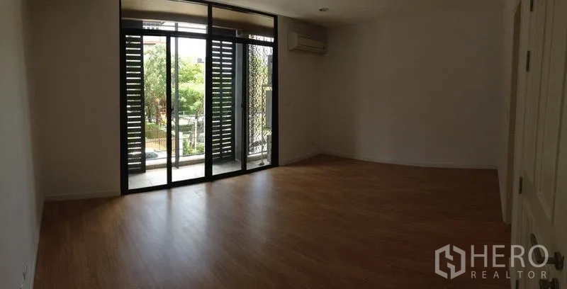 Townhouse for rent in Yan Nawa, Bangkok - Bedroom with sliding doors to a shaded balcony overlooking greenery.