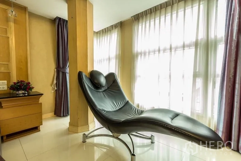 พื้นที่ขายปลีก ให้เช่า - มุมรับแสงด้วยเก้าอี้เอนหนังสีดำข้างผ้าม่านแบบเต็มความสูง