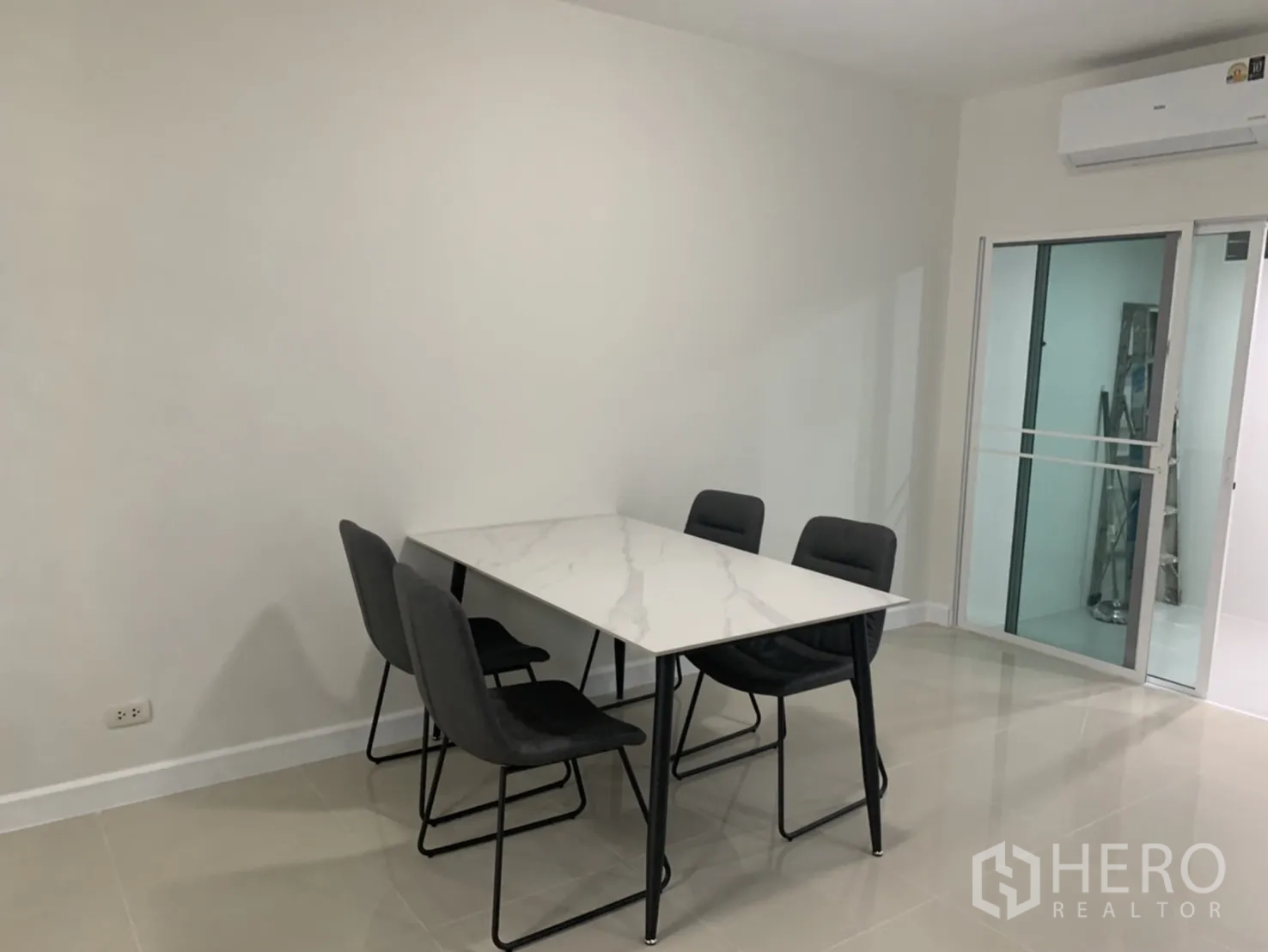 联排别墅 for rent in Bang Kapi, Bangkok - 餐区设大理石面餐桌和四把椅子，旁有玻璃隔断滑门。