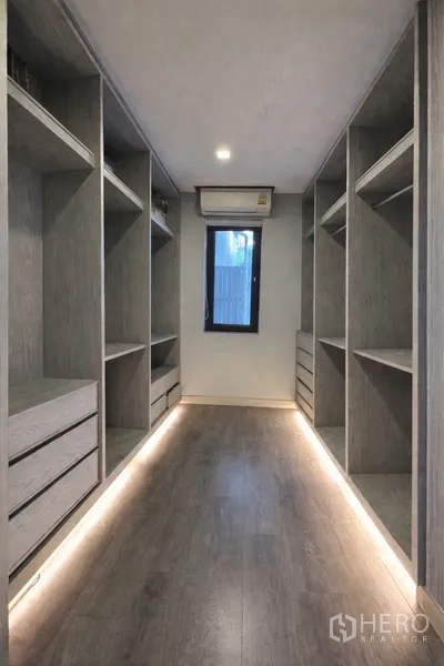 Semi-detached House for rent in Watthana, Bangkok - Walk-in closet with open shelves, drawers, and soft LED floor lighting.