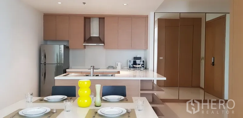 公寓 出租在Khlong Toei, Bangkok - 现代厨房设中岛台、炉灶与镜面储物柜。