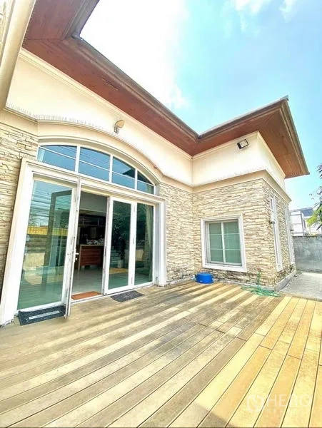 Home Office for rent in Pak Kret, Nonthaburi - Stone-clad home office exterior in Pak Kret with arched window, sliding glass doors and sunny wooden deck.