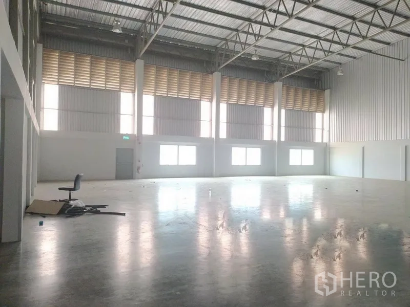 Warehouse for rent in Bang Sao Thong, Samut Prakan - Spacious warehouse interior with polished concrete floor, high steel-truss ceiling, windows and ventilation louvres.