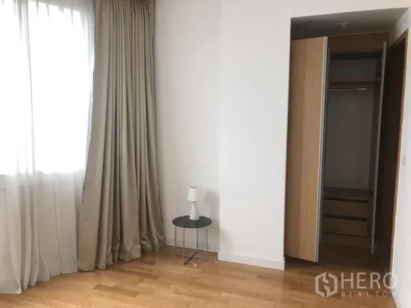 คอนโด ให้เช่าในKhlong Toei, Bangkok - มุมห้องนอน หน้าต่างบานใหญ่ ผ้าม่าน โต๊ะข้าง และตู้เสื้อผ้าเปิด