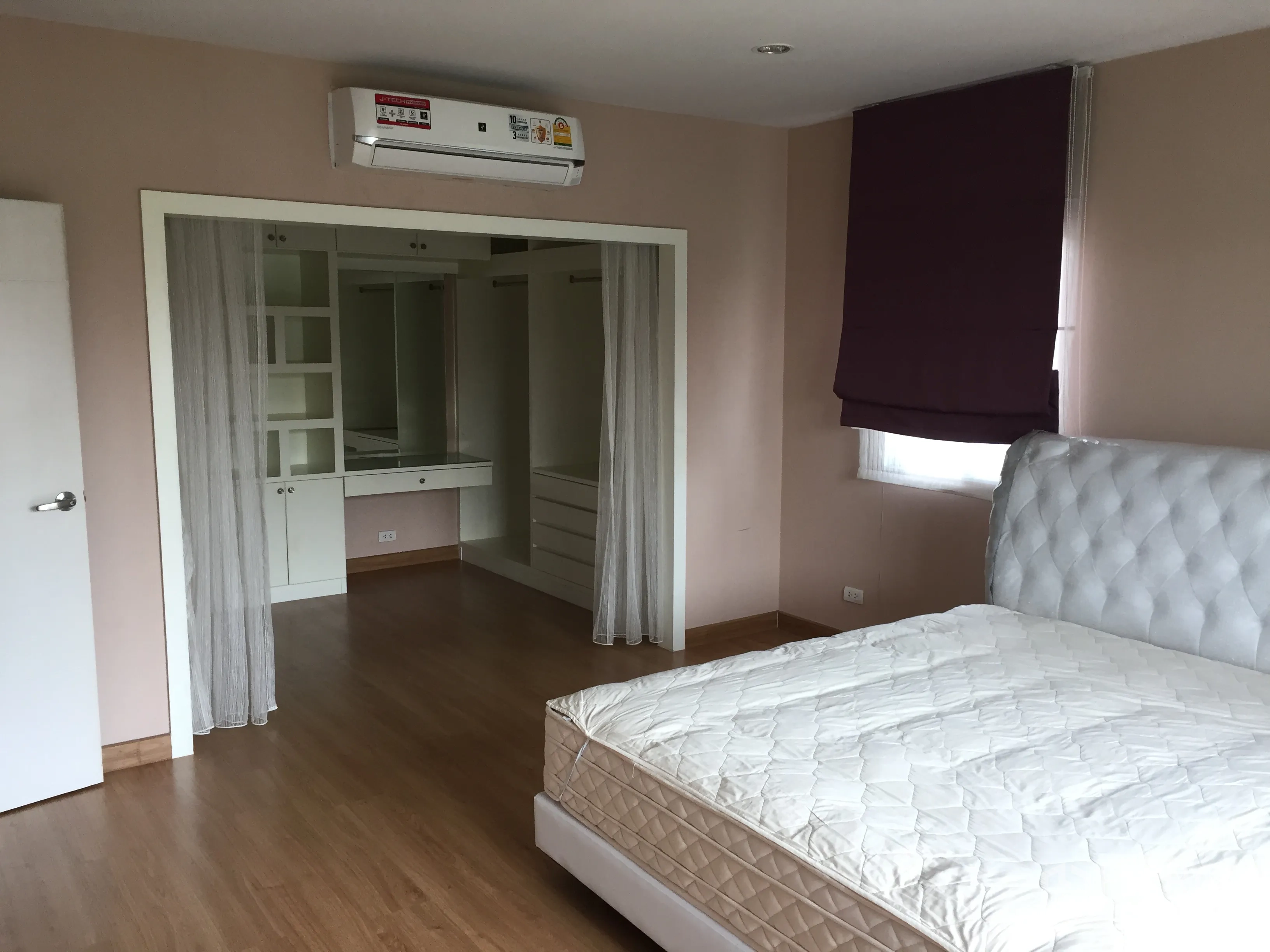 Detached House for rent in Pathum Thani - Master suite featuring a walk-in closet, dressing area and wall-mounted air conditioner.