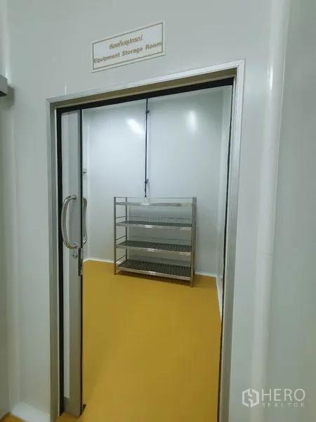 Factory for sale in Lam Luk Ka, Pathum Thani - Equipment storage room with stainless steel shelving seen through a sliding door.