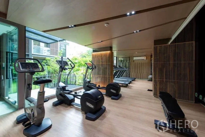 Condominium for rent in Huai Khwang, Bangkok - Gym with exercise bikes, weight machines and floor-to-ceiling windows.