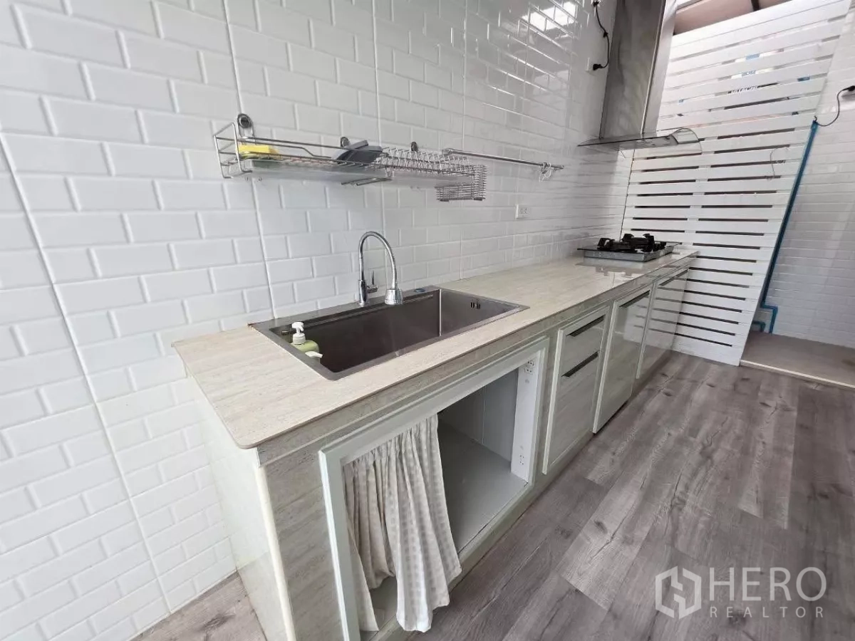 Detached House for rent or sale in Samut Prakan - Separate Thai kitchen with white subway tiles, gas hob and stainless-steel sink.