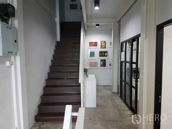店屋 出售在Bang Rak, Bangkok - 室内走廊与木楼梯，水泥地面，右侧为玻璃隔断办公室。