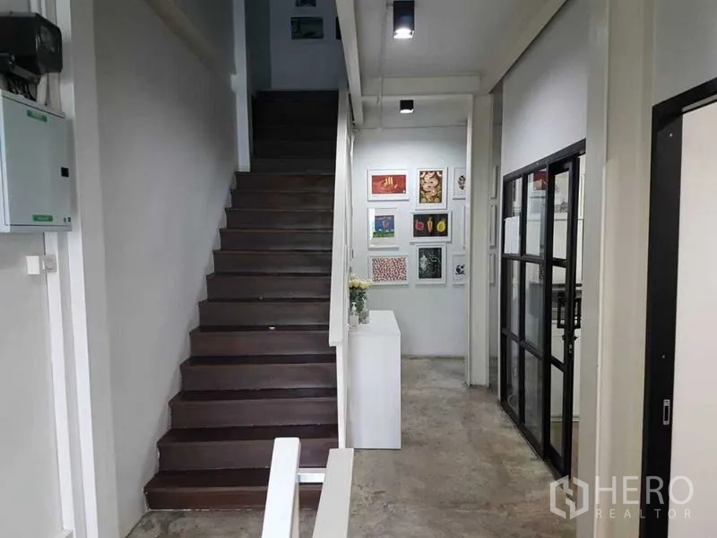 店屋 出售在Bang Rak, Bangkok - 室内走廊与木楼梯，水泥地面，右侧为玻璃隔断办公室。