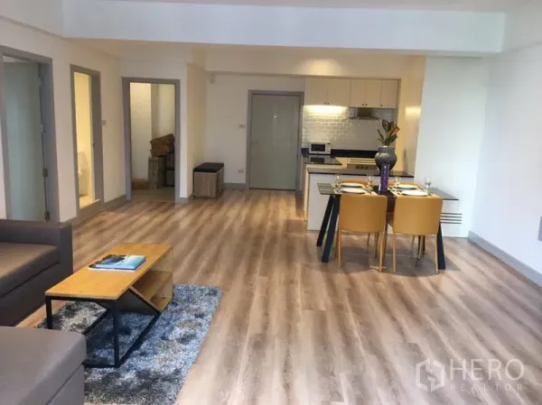 อพาร์ทเมนท์ ให้เช่าในKhlong Toei, Bangkok - โซนนั่งเล่นแบบโอเพ่นพร้อมโต๊ะทานอาหารและครัวขนาดกะทัดรัด พื้นไม้กว้าง