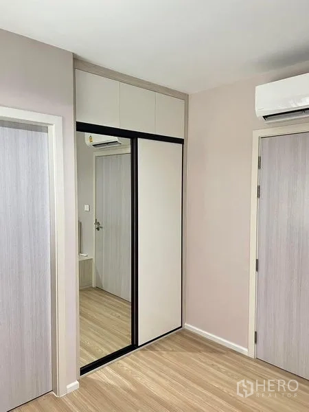 Townhouse for rent in Saphan Sung, Bangkok - Bedroom corner with sliding mirrored wardrobe, air conditioner and wood flooring.