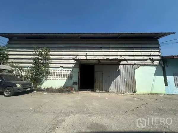 Warehouse for rent in Suan Luang, Bangkok - Front facade of the warehouse with metal sliding doors and a concrete loading apron.