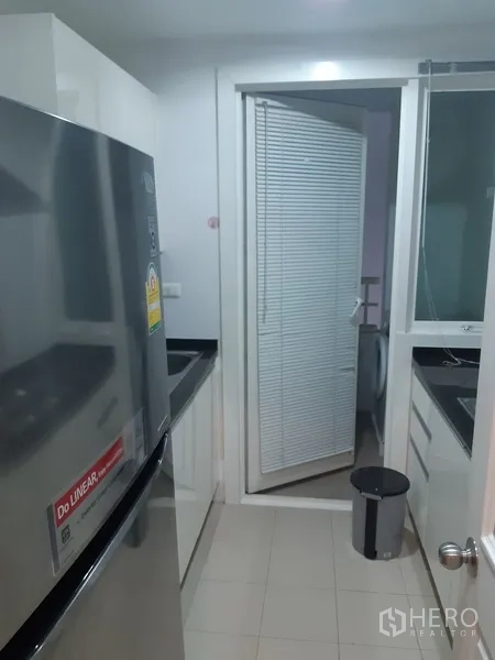 คอนโด ให้เช่าในKhlong Toei, Bangkok - ครัวปิดแบบแกลเลย์ แยกเป็นสัดส่วน มีตู้เย็น เคาน์เตอร์สีดำ และพื้นที่ซักล้างพร้อมเครื่องซักผ้า