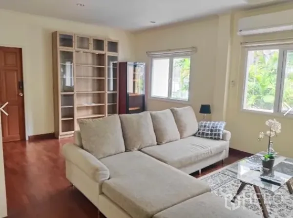Detached House for rent in Huai Khwang, Bangkok - Bright living room with L-shaped sofa, windows and built-in shelving