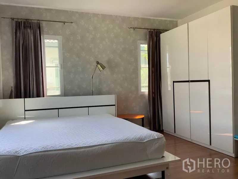 Detached House for rent in Bang Kapi, Bangkok - Master bedroom with large bed, glossy wardrobe and reading lamp by patterned wallpaper.