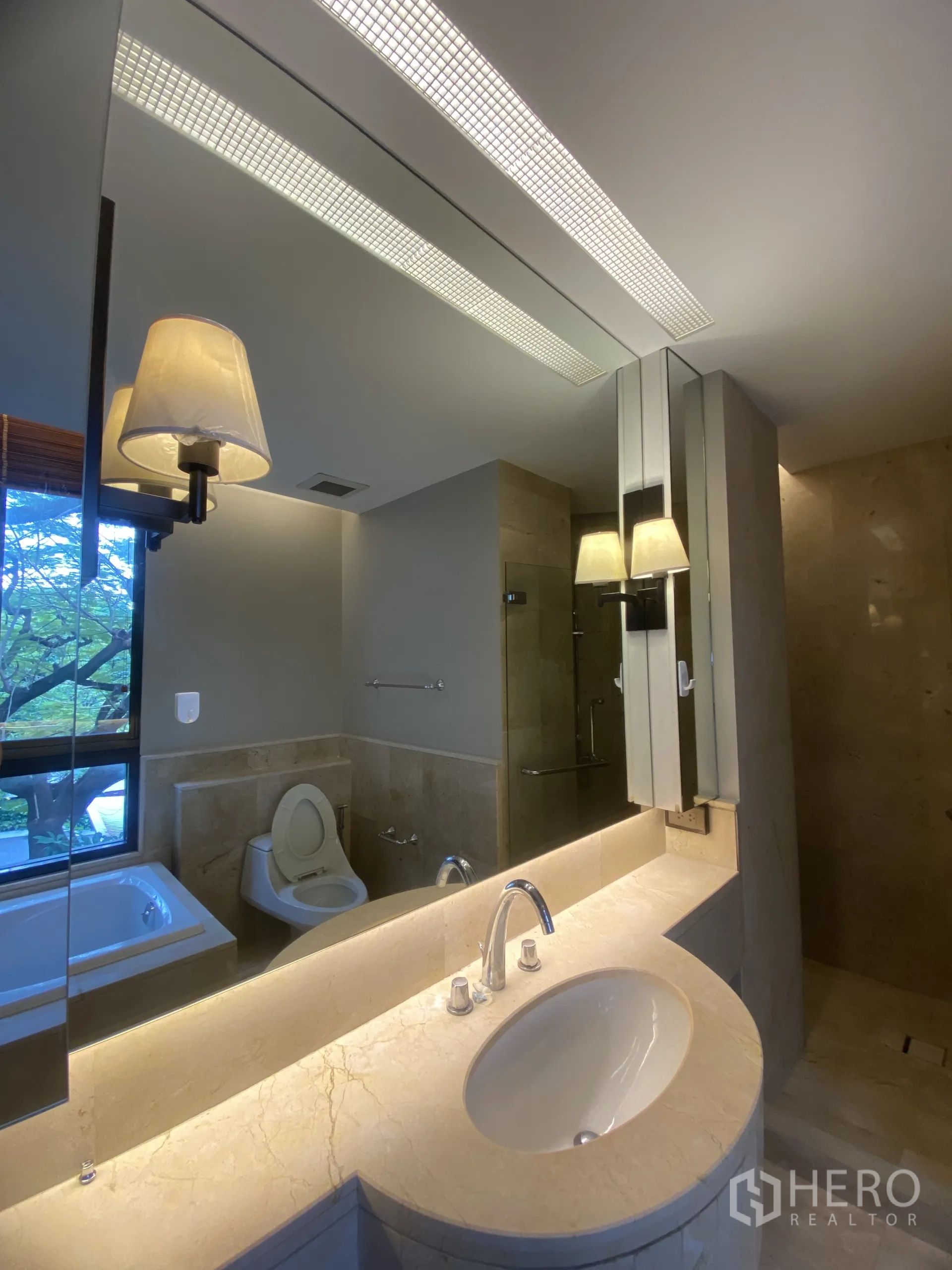 Condominium for rent in Watthana, Bangkok - Modern bathroom vanity with large mirror, sink, toilet, shower, and bathtub in view.