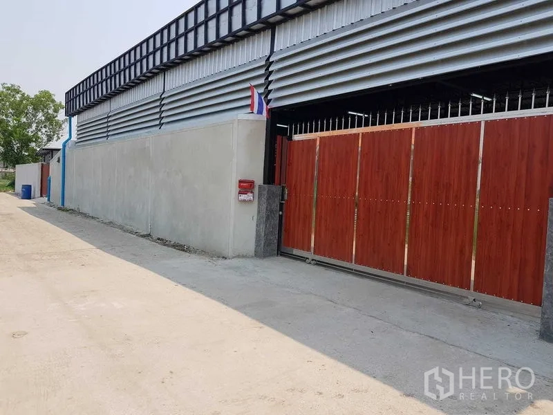 货栈 出售在Lam Luk Ka, Pathum Thani - Lam Luk Ka 区仓库外观，红色大型滑动门与混凝土围墙，临安静小路。