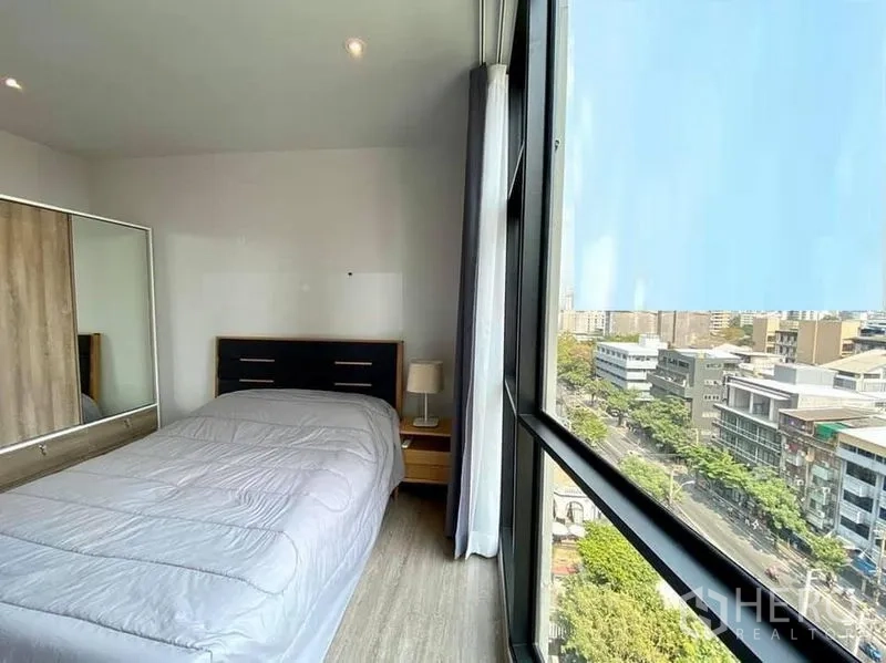 公寓 出租在Watthana, Bangkok - 明亮卧室，落地窗城市景观，带镜面衣柜和床头灯。