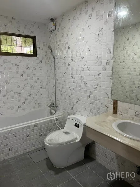Townhouse for rent in Watthana, Bangkok - Bathroom with white mosaic tiles, bathtub, handheld shower, and vanity.