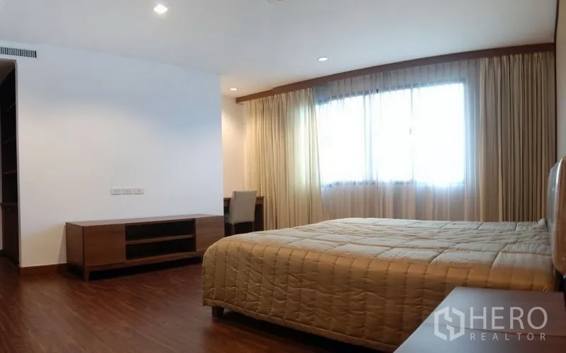 Condominium for rent in Watthana, Bangkok - Furnished bedroom with bed, wood flooring, media cabinet and sheer curtains.