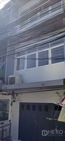 店屋 出租在Watthana, Bangkok - 三层店屋外立面，设宽大前门、窗户与外置空调机。