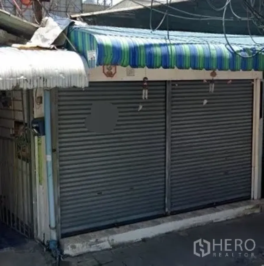 พื้นที่ขายปลีก ให้เช่าในWatthana, Bangkok - ด้านหน้าร้านติดถนน มีประตูม้วนโลหะคู่และกันสาดลายทางในซอยแคบ